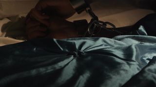 Sinnliche rothaarige MILF allein im Bett in einem BDSM-Porno mit Ketten