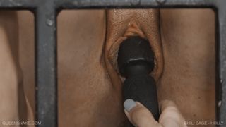 Nackte Frau in einem Käfig mit einem mechanischen Dildo in ihrer Muschi
